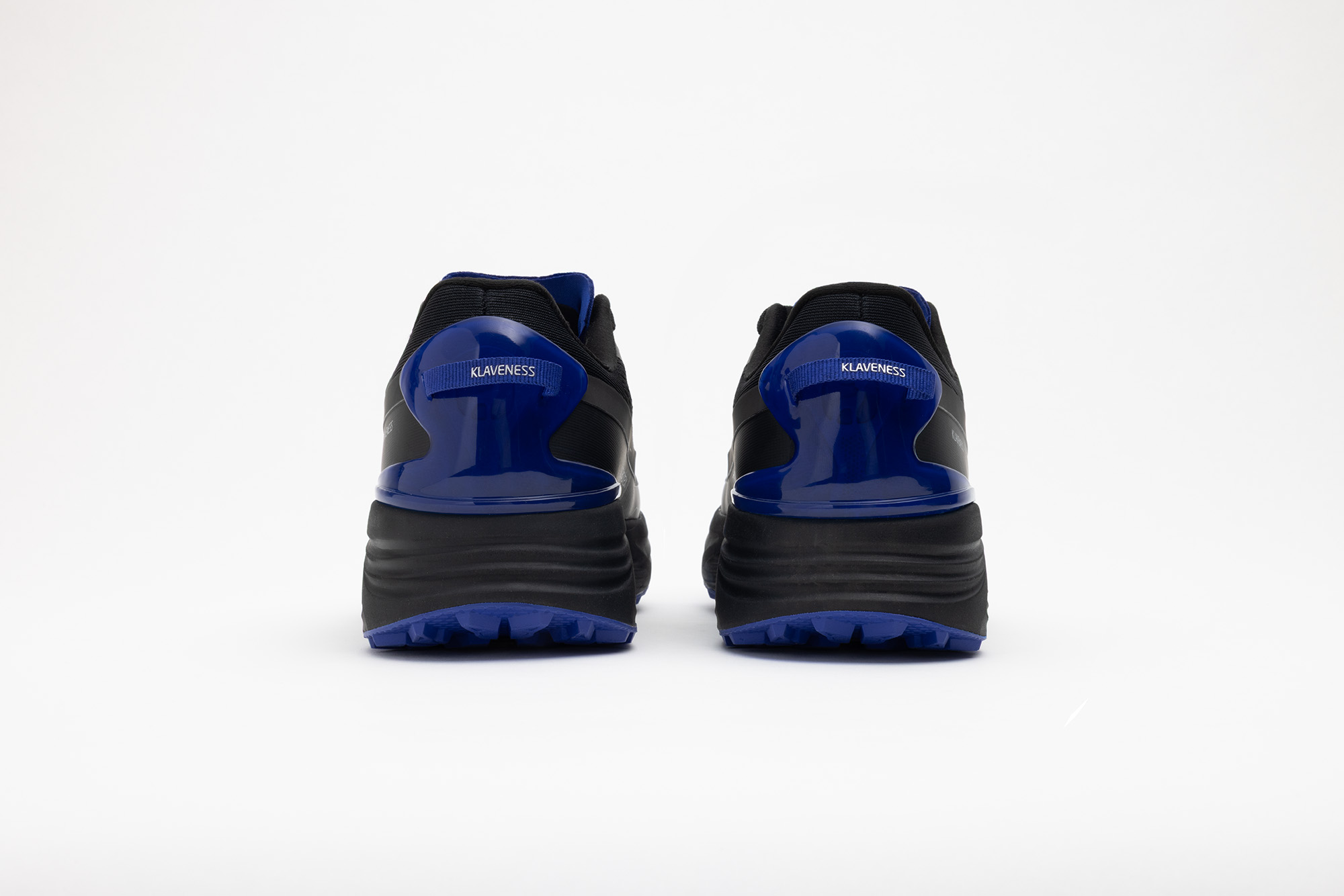 A pair of black PSGEN3 sneakers from behind, with cobalt blue heel counters.