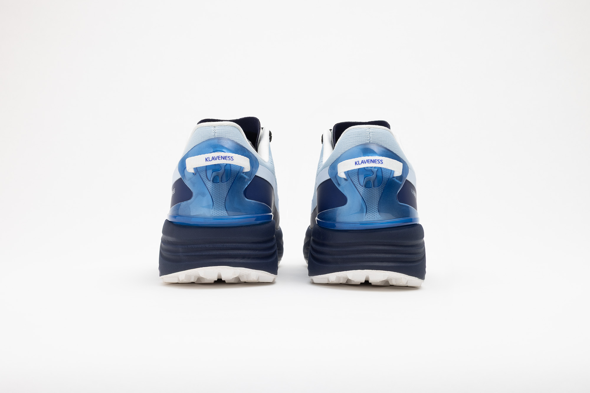 A pair of pale blue PSGEN3 sneakers from behind, with navy heel counters.